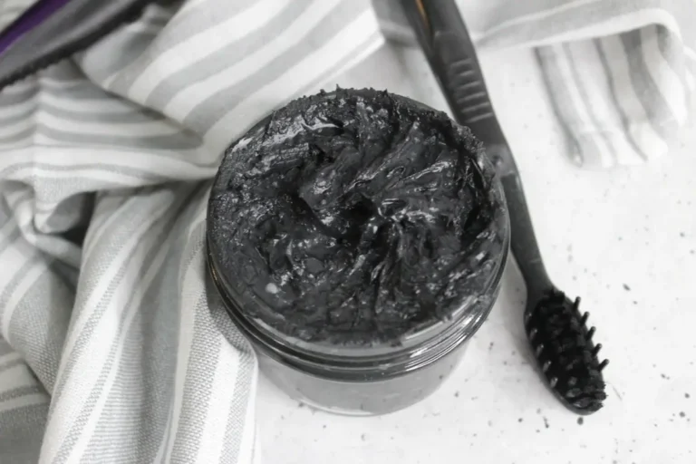 jar of homemade natural charcoal toothpaste with a toothbrush