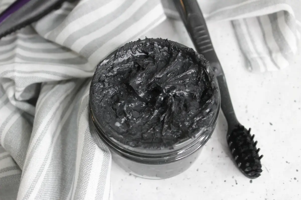 jar of homemade natural charcoal toothpaste with a toothbrush