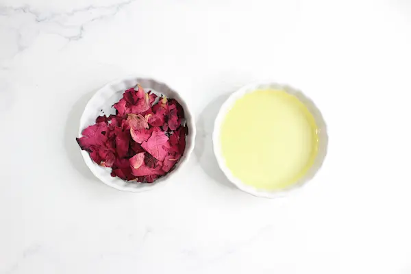 bowls of carrier oil and dried rose petals to make a rose infused oil for a diy tallow face cream