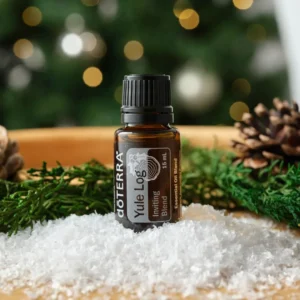 bottle of doTERRA Yule Log essential oil blend on artifical snow with Christmas scene in background