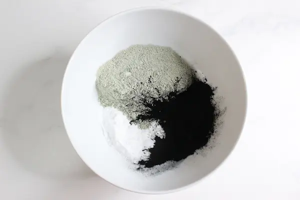 bowl of powders and charcoal for making homemade armpit detox paste