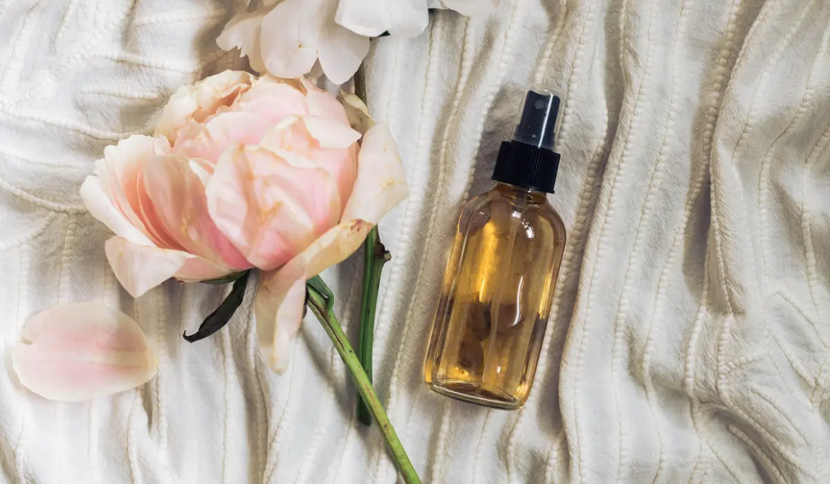 homemade linen sleep spray bottle on cream colored duvet with roses