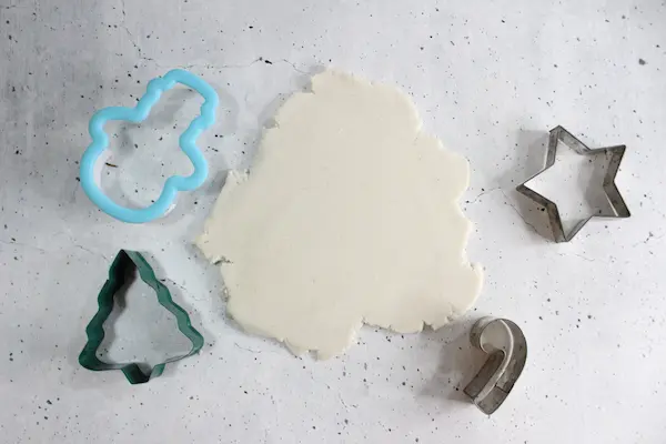 rolled out dough for no bake diffuser ornaments surrounded by Christmas cookie cutters