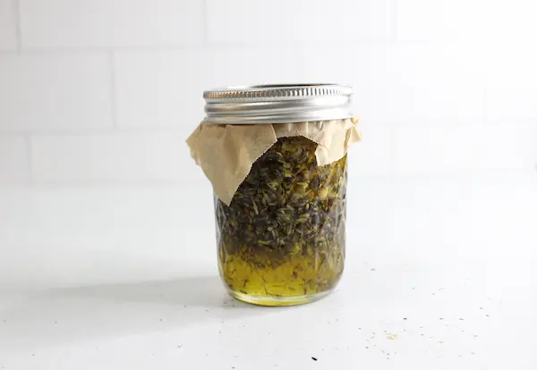 jar of infused oil with lavender and chamomile herbs to be used to make homemade sleep salve