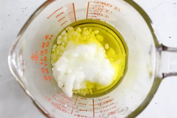 glass measuring cup with melted butters and beeswax to make a homemade sleep salve