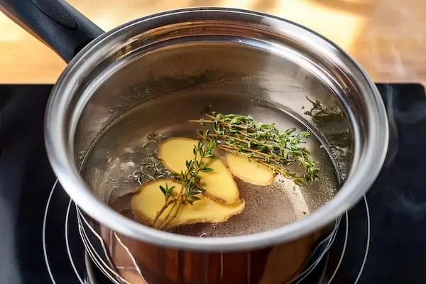 Thyme Cough Syrup With Honey Lemon & Ginger DIY Recipe 13 a small saucepan with sliced ginger and springs of thyme for making homemade honey