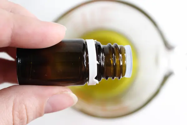 adding drops of essential oil into melted green tea lip balm mixture