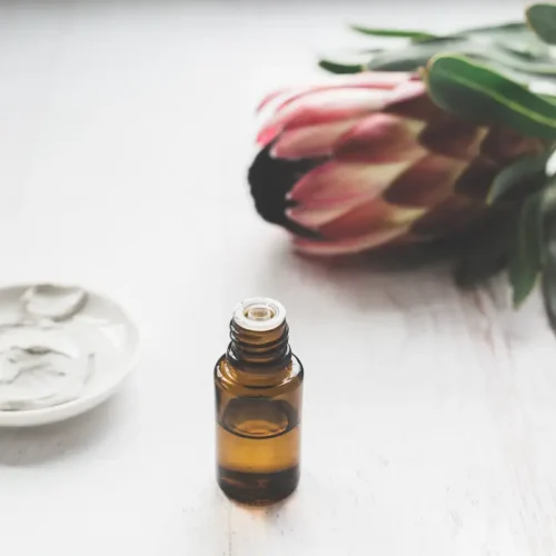 bottle of essential oil, a flower and a jar of skin care cream