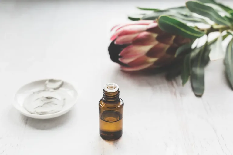 bottle of essential oil, a flower and a jar of skin care cream