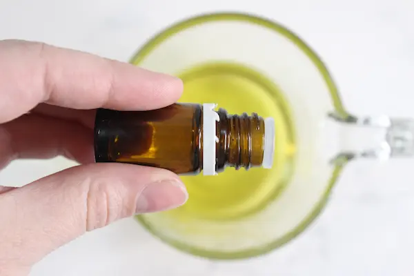 adding essential oil to melted ingredients for making tallow lip balm