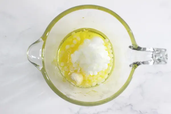 a glass jar of butters and waxes to melt down to make tallow lip balm