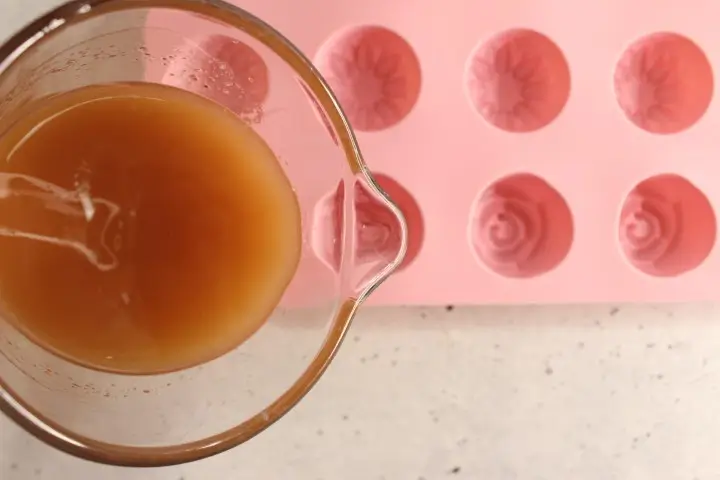 Moisturizing Rose Lotion Bars DIY Recipe 22 pouring melted oils into a silicone mold to make diy rose lotion bars