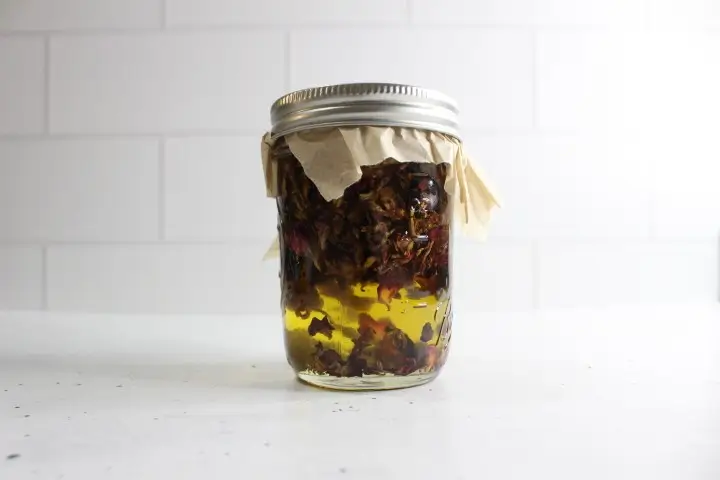 Moisturizing Rose Lotion Bars DIY Recipe 17 glass mason jar filled with carrier oil and dried rose petals for making a rose infused carrier oil to use in diy rose lotion bars
