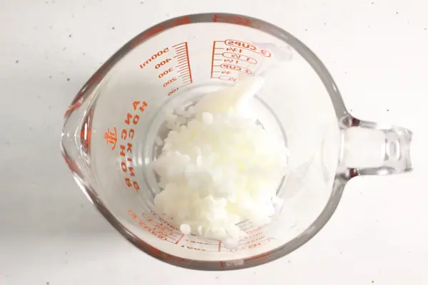 Magnesium Tallow Lotion Balm DIY Recipe 18 a glass measuring cup with beeswax in it for making magnesium tallow balm