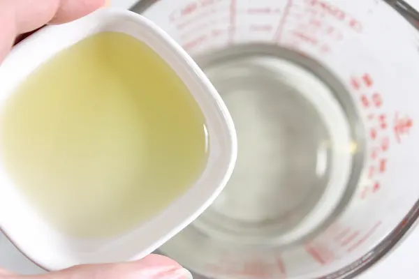 Magnesium Tallow Lotion Balm DIY Recipe 20 adding a bowl of almond oil to a glass measuring cup containing melted tallow and beeswax