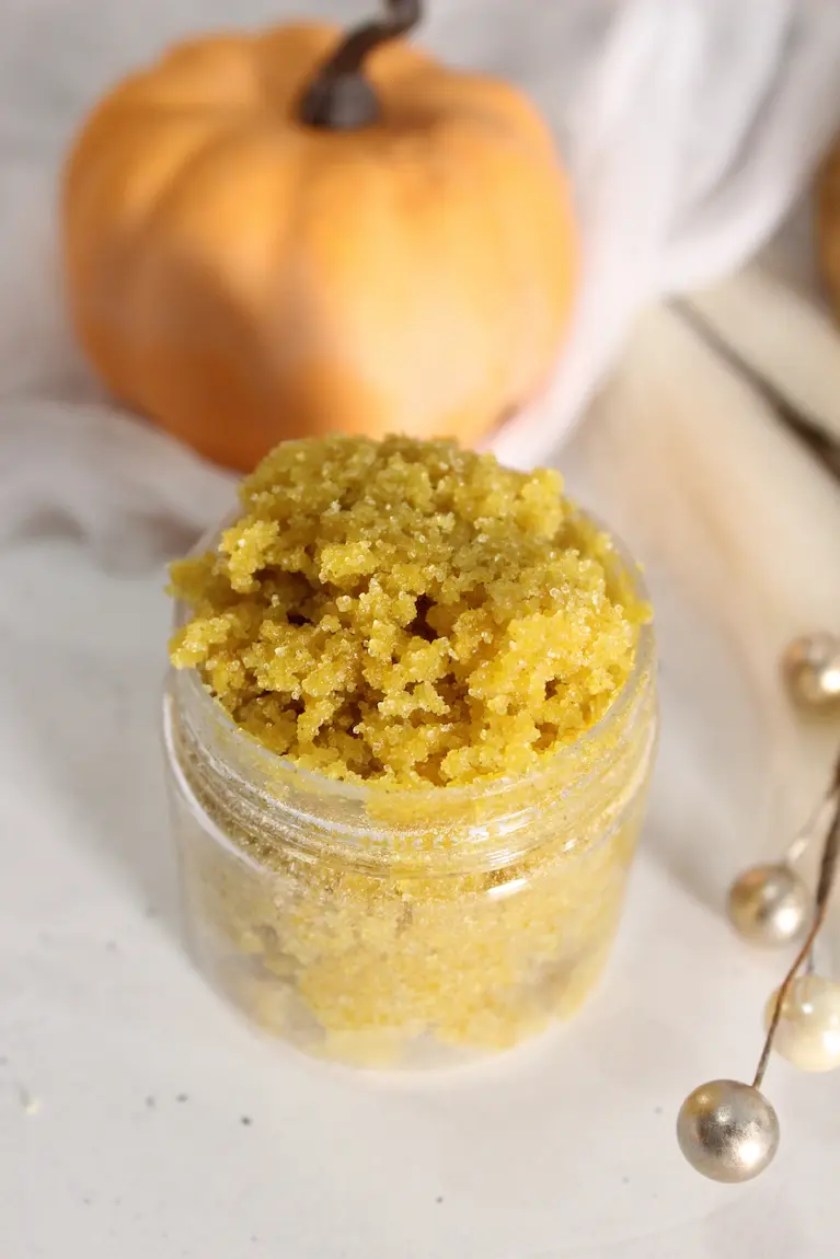 a jar of homemade pumpkin sugar scrub with a pumpkin in the background