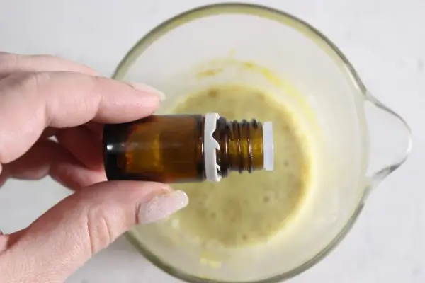a bowl of melted soap base with pumpkin spice powder and a bottle of essential oil