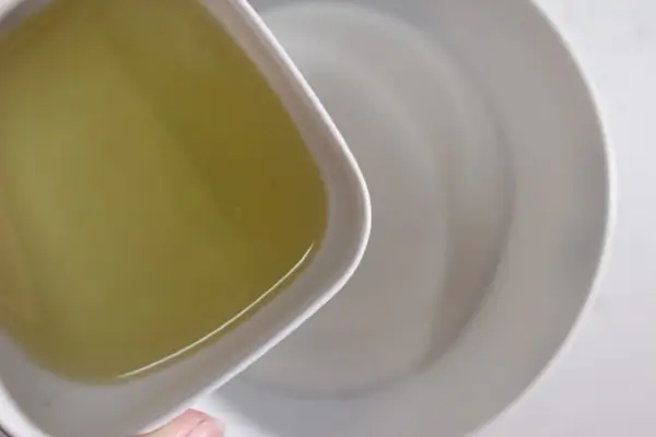 adding candy cane scented oil to a bowl of sugar for making a sugar scrub
