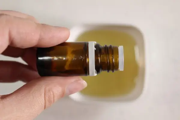 adding essential oil to a bowl of carrier oil to make candy cane sugar scrub