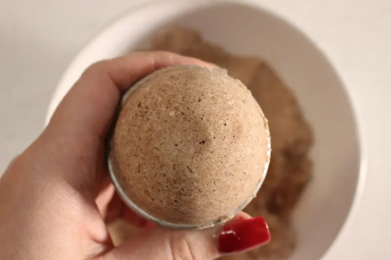 Rose Chocolate Bath Bomb Recipe 23 woman's hand holding a chocolate bath bomb over a bowl