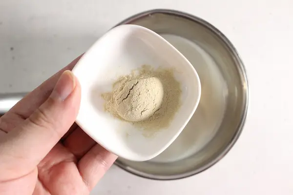 Blue Moon Milk Recipe with Butterfly Pea Flower and Ashwagandha For Sleep and Stress 17 bowl of ashwagandha powder being added to warm milk