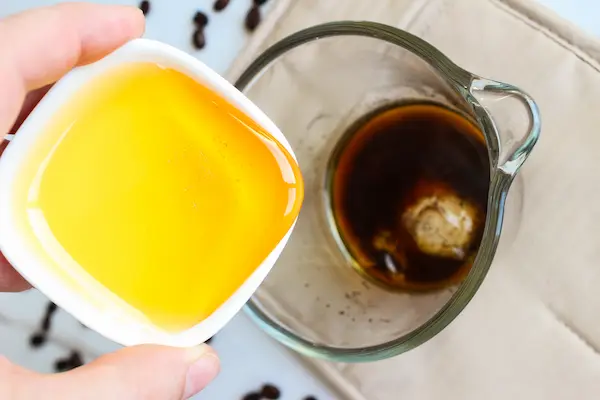 Under Eye Coffee Patches DIY Recipe 17 a bowl of coffee and a hand pouring a bowl of honey into the coffee to make diy coffee eye patches