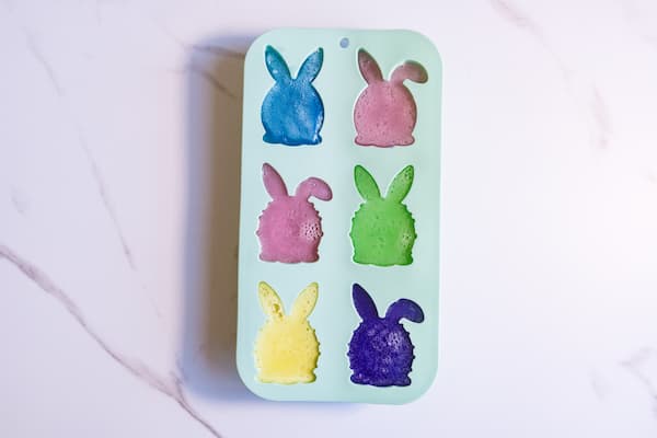 a silicone easter bunny soap mold filled with colored soap mixture