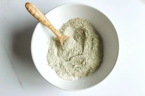 Lavender Tallow Oatmeal Face Scrub Recipe 17 a mixing bowl and wooden spoon with mixture in it to make lavender tallow face scrub