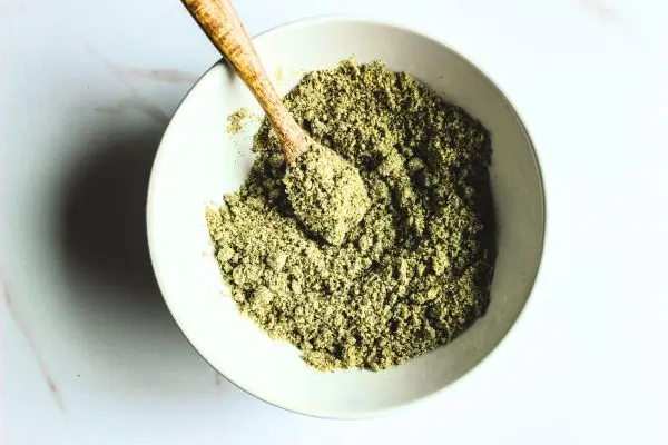 Lavender Tallow Oatmeal Face Scrub Recipe 21 a mixing bowl and wooden spoon with homemade lavender tallow mixture in it.