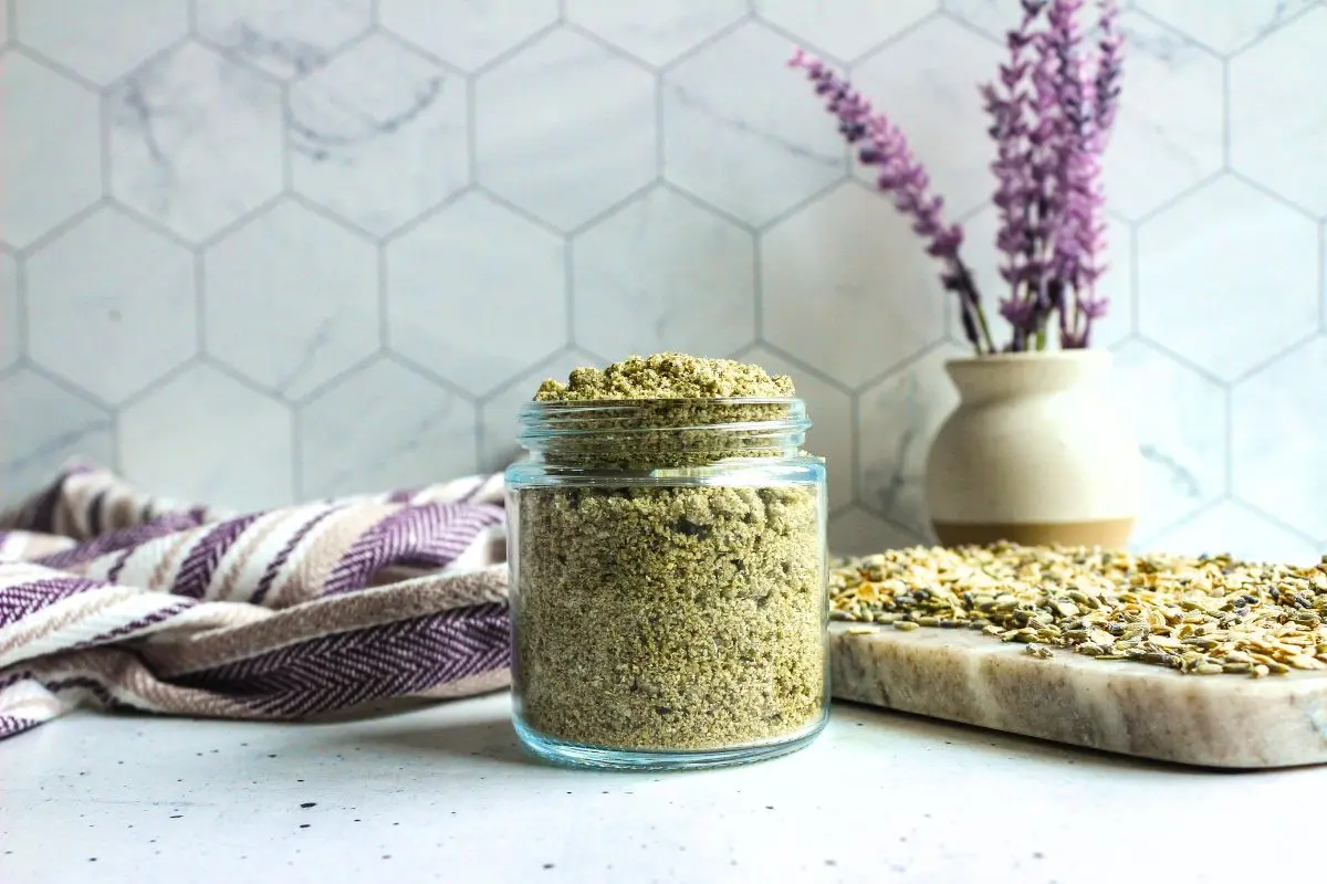 jar of homemade lavender tallow oatmeal face scrub with lavender sprig in the background