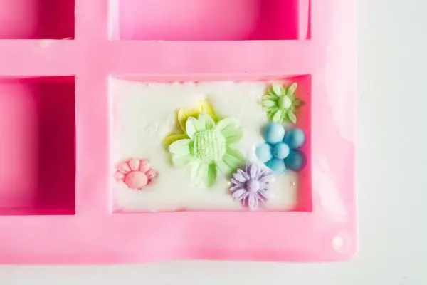 DIY Floral Soap Bars - an impressive handmade gift 35 a pink silicone soap mold with white soap and colored flowers in it.
