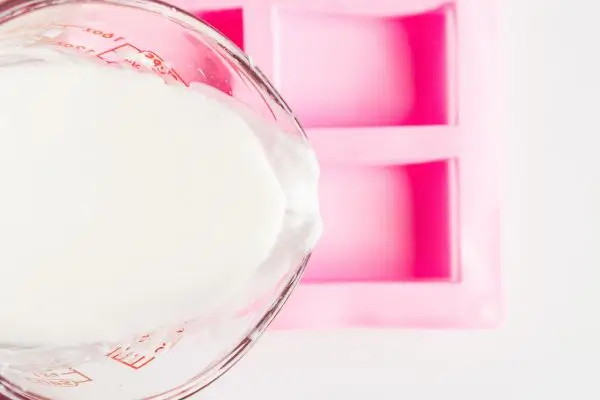 DIY Floral Soap Bars - an impressive handmade gift 34 a pink silicone soap mold with melted soap base being poured into from a glass measuring cup