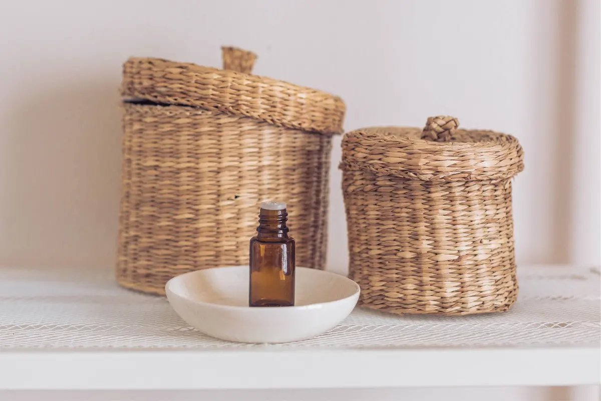 Essential Oil Recipes: Complete Guide to Diffusing, Rollers, Sprays & More 2 a bottle of essential oil in front of wicker baskets for a post on an essential oils guide for how to use oils